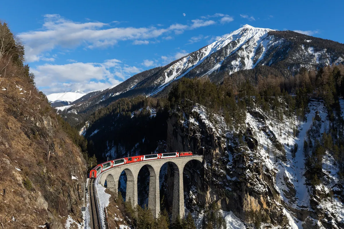 Red Glacier Express train crossing the curved stone Landwasser Viaduct on the Albula line in Graubünden